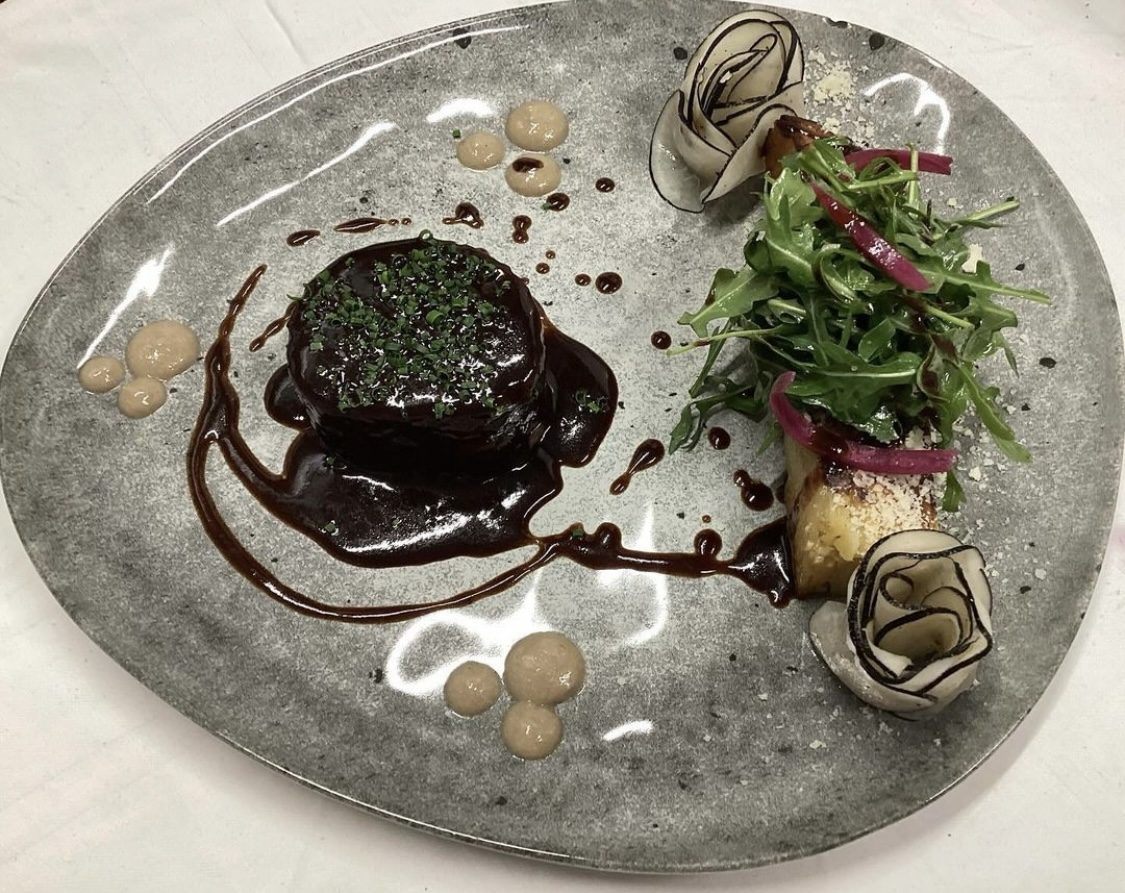 Une pièce de viande nappée de jus, accompagnée de salade et de condiments